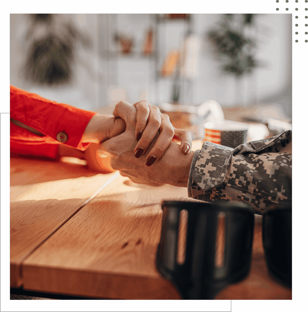 Hands holding across table, military uniform.
