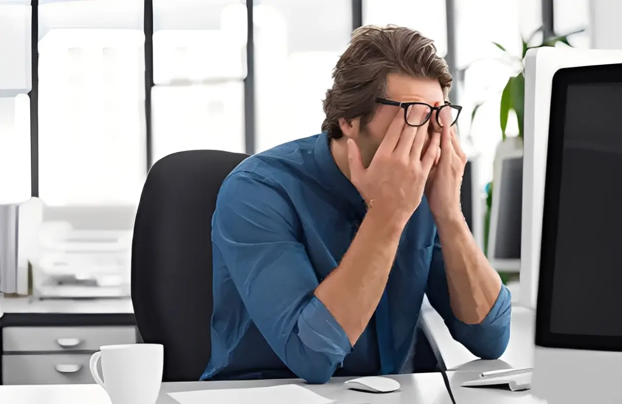 Man stressed at desk with computer.