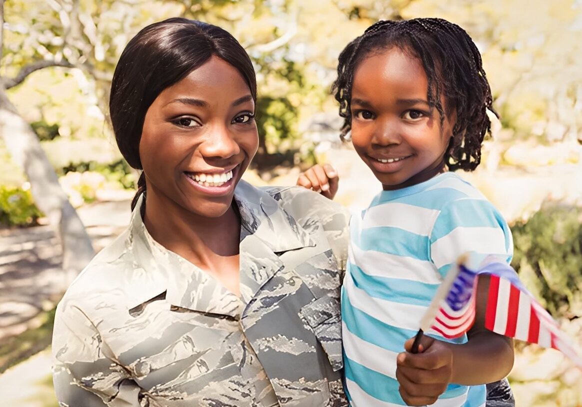 Smiling soldier with child holding flag.