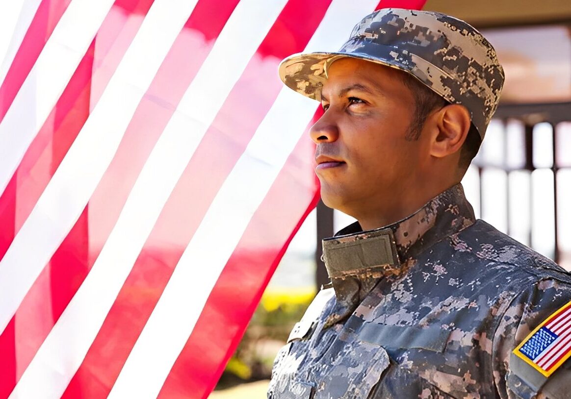 Soldier in uniform beside American flag.